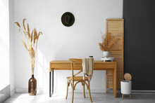 Modern Workplace And Vases With Dry Reeds Near Light Wall