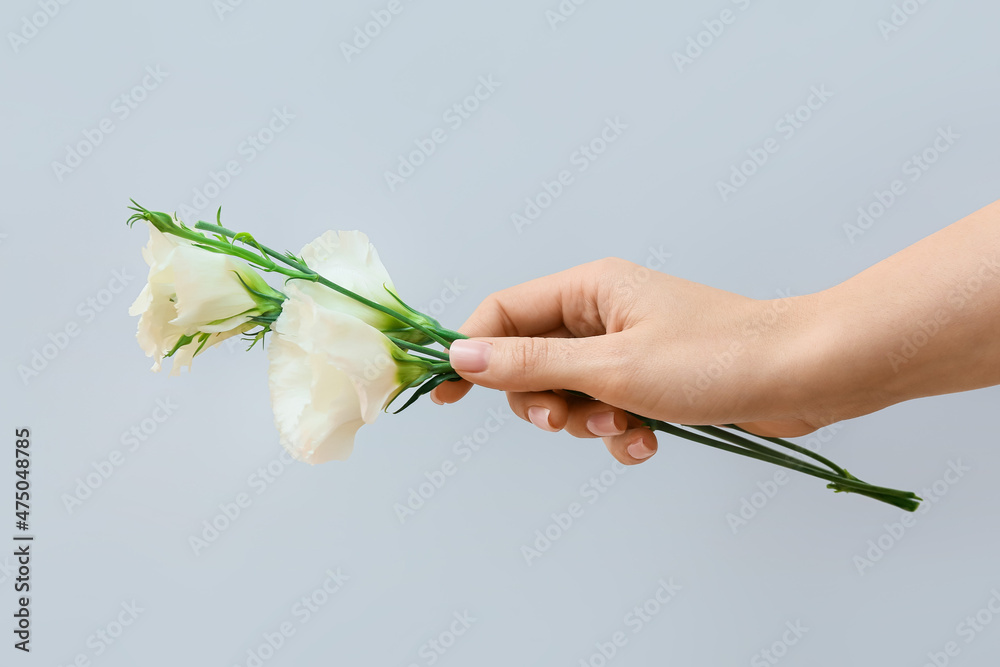 Woman with beautiful manicure holding flowers on grey background