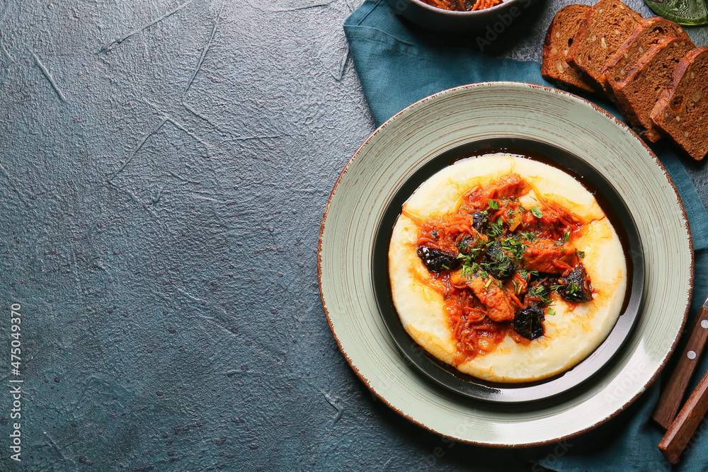 Plate with delicious mashed potatoes, gravy sauce and beef stew with prunes on dark background