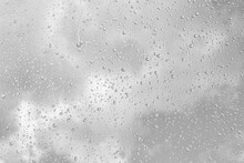 Rain Drops On Window Glasses Surface With Gray Sky Background. Natural Backdrop Of Raindrops. The Concept Of Bad Rainy Weather.