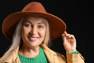 Poster - Portrait of fashionable mature woman in felt hat on dark background