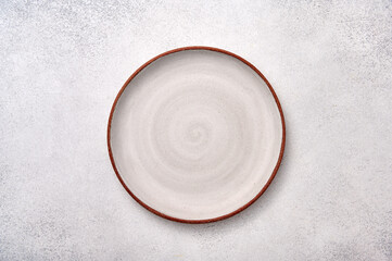 empty white ceramic plate with brown rim on a light textured background, top view, copy space