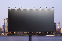 Blank Black Billboard On City Buildings Background At Night, Front View. Mockup, Advertising Concept