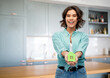 © Syda Productions - eco living, environment and sustainability concept - portrait of happy smiling young woman in turquoise shirt holding green house at home over kitchen background