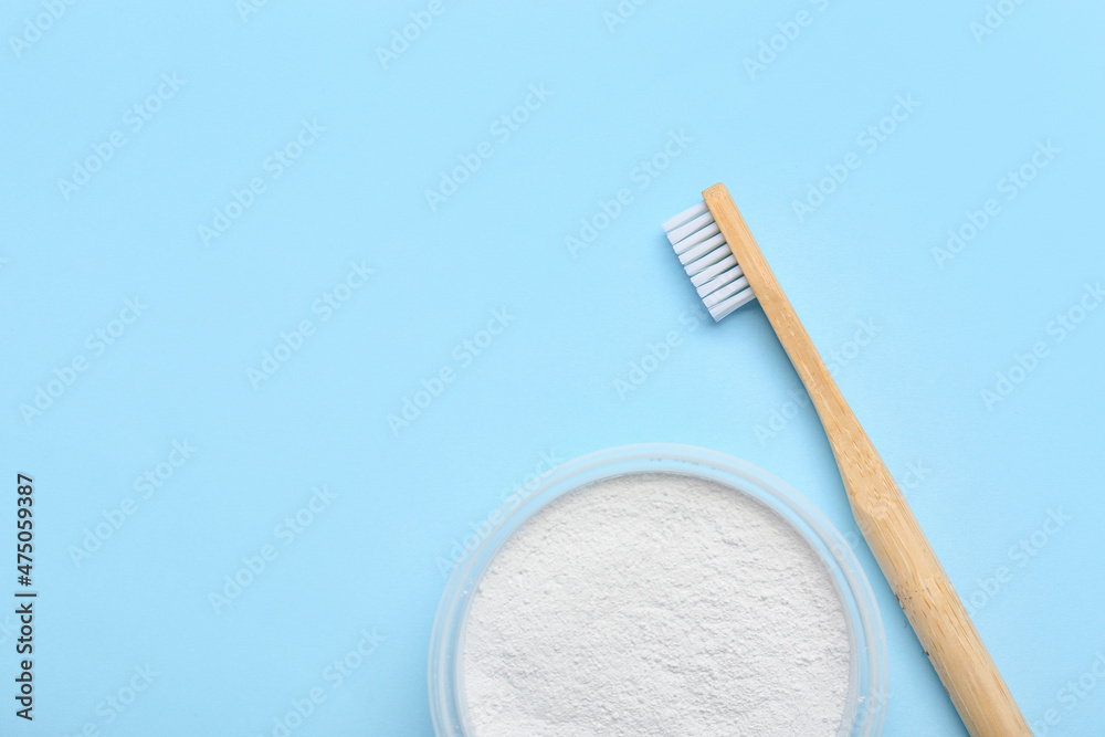 Wooden toothbrush and powder on blue background, closeup