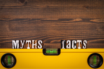 Myths and Facts Balance concept. Yellow spirit level on a wooden background