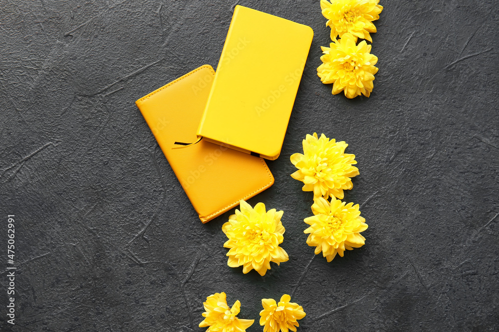 Yellow chrysanthemum flowers and notebooks on dark background