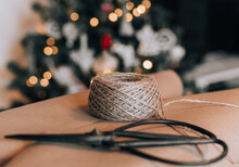 Close-up Photo Of Wrapping Paper, Twine And Scissors In Front Of Christmas Tree