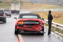 Accident On The Road. A Broken-down Ford Mustang Convertible With A Female Car Driver Standing Next To It.