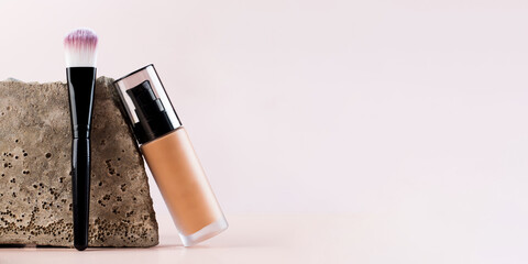 Banner cosmetic brush and foundation next to a grey stone. Copy space.