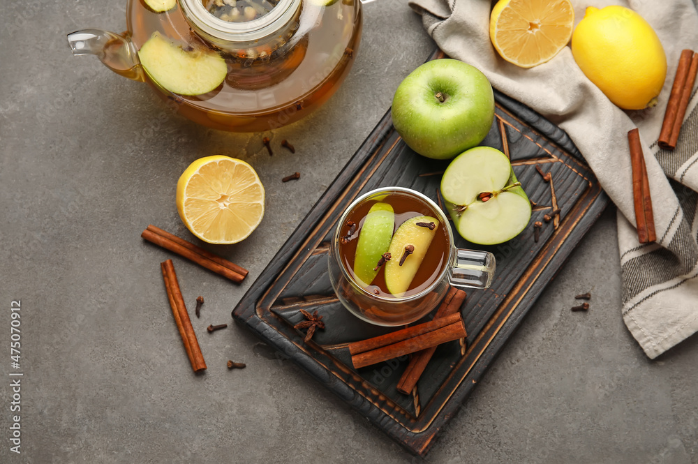 Glass cup of tasty fruit tea with cinnamon on grey background