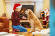 © Dragana Gordic - Photo of young woman and her dog enjoying together at home in a Christmas atmosphere. Best christmas present ever. Young woman sitting on the floor and playing with dog on a New year's eve