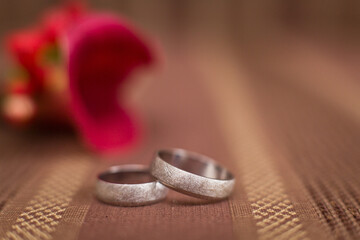 Wall Mural - Two wedding rings on a background from red flowers