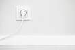 © Paweł Michałowski - Electrical socket isolated on gray wall. White wire plug plugged in. Renovated studio apartment power supply background. Empty copy space double white plastic power outlet.