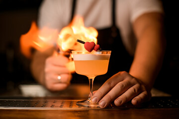great view on decorative heart on glass with foamy cocktail on background of fiery flame