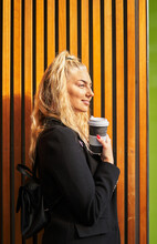 Young Blonde Woman With Takeaway Coffee And Backpack