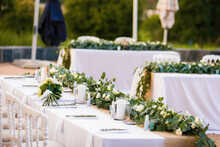 Delicate Arrangement Of Wedding Venue Tables Decorated With White Water Lilies And Candles Outdoors