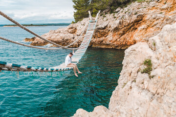 Wall Mural - man sitting at suspension bridge enjoying sea view and nature calmness