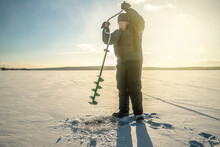 Fisherman Is Fishing In A Hole On A Large Frozen Lake On A Sunny Day. The Joy Of Winter Fishing