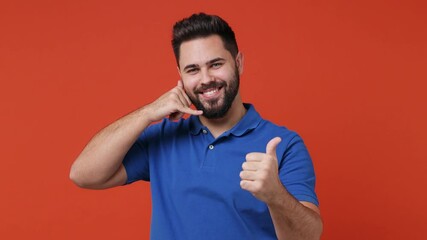 Wall Mural - Young bearded brunet man 20s wears blue t-shirt point finger camera on you doing phone gesture like says call me back show thumb up like gesture isolated on plain red orange background studio portrait