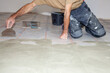 Construction worker leveling compound with putty knife. Renovation, floor leveling screed, mass distribution. Preparation for an even floor to installing a new vinyl as a floor covering in the kitchen