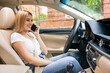 Attractive businesswoman smiling while talking on the phone and driving to work.