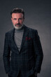 © .shock - Portrait of a stylish elegant senior businessman with a beard and casual business clothes in photo studio isolated on dark background gesturing with hands