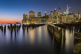 Fototapeta Miasto - View of lower Manhattan at dusk seen from Brooklyn. Remaining of an old pier can be seen at the foreground and city skyline in the background