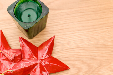 Wall Mural - red wooden stars Christmas decoration and green candle on a wooden background