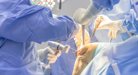 Wall Mural - A team of doctor doing orthopaedic surgery inside modern operating room in hospital.Photo intension to blurred.Surgeon and nurse in blue gown suite.Medical concept.A blur photo for background.