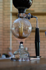 Sticker - Vertical shot of a glass syphon coffee maker on the table with a blurry background