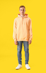 Wall Mural - Young guy in stylish hoodie on color background