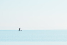 Beautiful View Of A Man Standing On A Paddling Boat In The Blue Sea