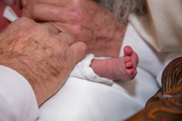 Canvas Print - Closeup of an old person touching the feet of an adorable newborn baby