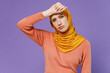 Young arabian asian muslim woman in abaya hijab yellow clothes put hands on head rub temples having headache suffering from migraine isolated on plain pastel light violet background studio portrait.