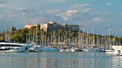 Wall Mural - View of the sea port in Antibes, France. Moored boats and yachts, Fort Carre on the background, greenery