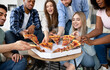 © Prostock-studio - Happy multiracial friends chatting, eating pizza together, having small party at home