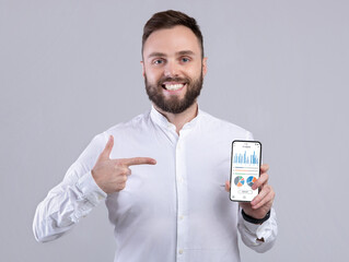 Poster - Happy businessman holding phone with analytics app on screen