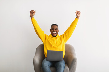 Wall Mural - Black Man With Laptop Shaking Fists In Joy, Gray Background