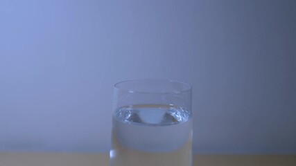 Wall Mural - Zoom-out footage of a glass of mineral water standing next to a lemon on a white background