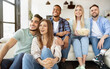 Group of cheerful young friends enjoying movie at home, eating popcorn and smiling