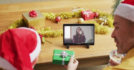 Poster - Caucasian father and son with santa hats using tablet for christmas video call with woman on screen