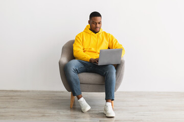 Sticker - Black Guy Using Laptop Working Online Sitting On Gray Background