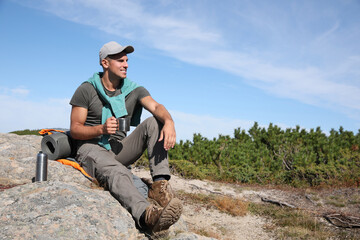 Canvas Print - Tourist with hot drink, sleeping bag and mat on mountain peak