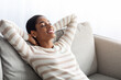 © Prostock-studio - Home Comfort. Relaxed Black Female Sitting On Couch With Closed Eyes