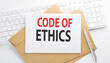 © Iryna - Text CODE OF ETHICS on the envelope on the keyboard