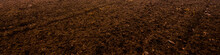 Plowed Agricultural Field, Tractor Tracks, Soil Texture Close-up. Rural Scene. Panoramic Landscape. Farm And Food Industry, Alternative Energy And Production, Environmental Conservation Theme