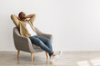 © Prostock-studio - Happy African American Man Relaxing Sitting In Chair, Gray Background