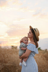 Canvas Print - Happy mother with adorable baby in field at sunset