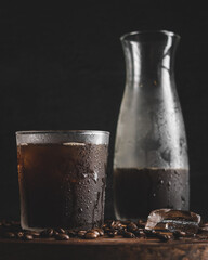 Sticker - Vertical closeup of a glass of cold coffee with a bottle in the background.